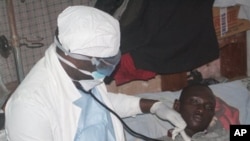 A health worker examines a man suffering from Ebola at a treatment center in Monrovia, Liberia, Oct. 15, 2014. 