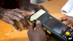 An elderly Nigerian woman validates her voting card using a fingerprint reader, prior to casting her vote later in the day, in the home town of opposition candidate Gen. Muhammadu Buhari, in Daura, Nigeria, March 28, 2015. 