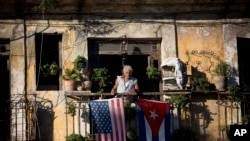 Dalam foto tertanggal 19/12/2014 ini, seorang warga Kuba Javier Yanez berdiri di balkoni rumahnya di Havana, dimana ia menggantungkan bendera Amerika dan Kuba setelah mendengar berita pencairan hubungan AS- Kuba. 