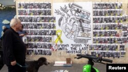 People walk next to a graffiti supporting the release of all hostages who have been held in Gaza since the deadly October 7, 2023 attack, in Tel Aviv