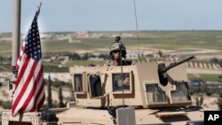 FILE - A U.S. soldier sits atop an armored vehicle, in Manbij, Syria, April 4, 2018. 