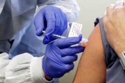 FILE - A subject receives a shot in the first-stage safety study clinical trial of a potential vaccine by Moderna for COVID-19, the disease caused by the new coronavirus, at the Kaiser Permanente Washington Health Research Institute in Seattle.