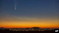 The Comet Neowise or C/2020 F3 is seen before sunrise over Balatonmariafurdo, Hungary, Tuesday, July 14, 2020. It passed closest to the Sun on July 3, and its closest approach to Earth will occur on July 23. (Gyorgy Varga/MTI via AP)