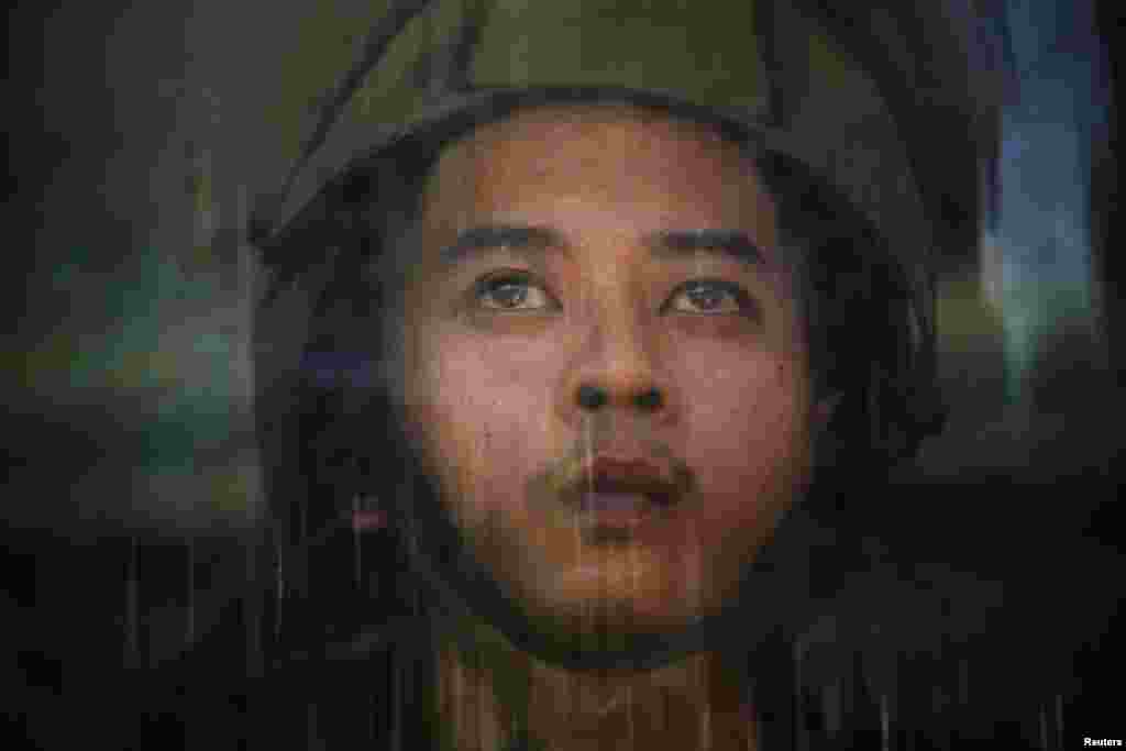 An Air Force member perspires behind his shield after anti-government protesters seeking to oust Thailand's government broke into an air force base in Bangkok, May 15, 2014. 
