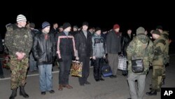 Warga Rusia (membelakangi kamera, sebelah kanan) dan militer Ukraina bersiap untuk pertukaran tahanan perang di luar wilayah Donetsk, Ukraina Timur (26/12).