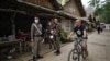 Seorang migran Karen yang tinggal di Thailand bersepeda melewati polisi Thailand di kota Mae Sam Laep di sisi sungai Salween di Thailand di provinsi Mae Hong Son pada 2 April 2021, di seberang tempat pengungsi Myanmar sebelumnya berusaha melintasi perbatasan Thailand. (Foto: AFP)