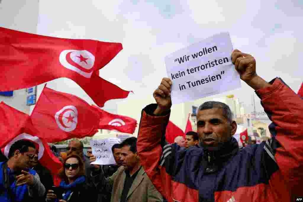 Tunisians wave banners and their national flag during a demonstration in Midoun, northeast of Djerba, two days after gunmen attacked the National Bardo Museum. The attack which killed 21 people, was the country's worst since the 2011 uprising that toppled leader Zine El Abidine Ben Ali. German writting on placard reads: "We don't want any terrorists in Tunisia."